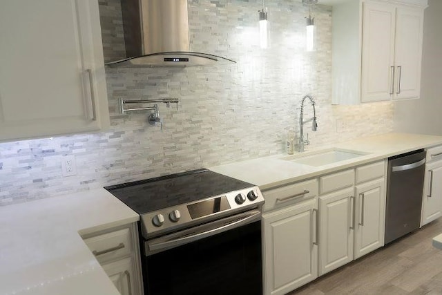 kitchen with light hardwood / wood-style floors, sink, white cabinets, wall chimney exhaust hood, and appliances with stainless steel finishes