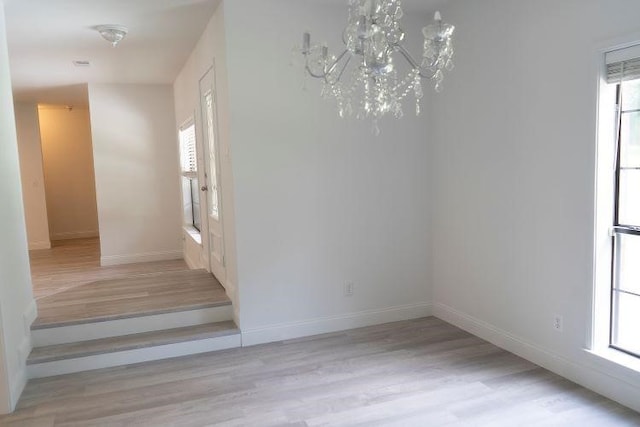 interior space with light wood-type flooring, an inviting chandelier, and a wealth of natural light