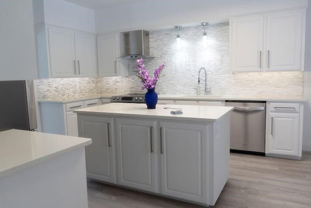 kitchen featuring wall chimney exhaust hood, white cabinetry, sink, and stainless steel dishwasher