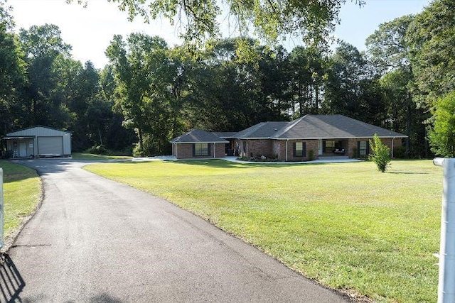 single story home featuring a garage, a front yard, and an outbuilding