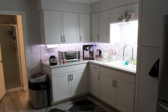 kitchen featuring light hardwood / wood-style flooring, white cabinetry, tasteful backsplash, and sink