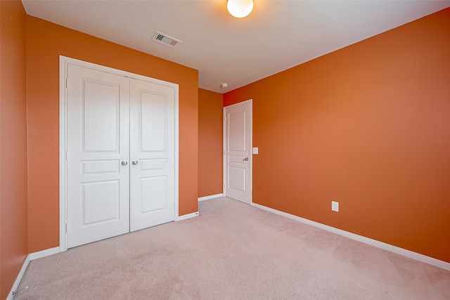 unfurnished bedroom featuring light colored carpet and a closet