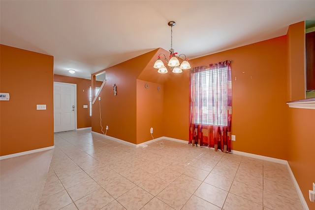 tiled spare room with an inviting chandelier