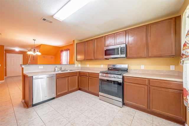 kitchen featuring hanging light fixtures, vaulted ceiling, kitchen peninsula, stainless steel appliances, and a chandelier