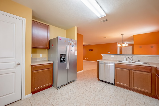 kitchen featuring a textured ceiling, sink, a notable chandelier, hanging light fixtures, and appliances with stainless steel finishes