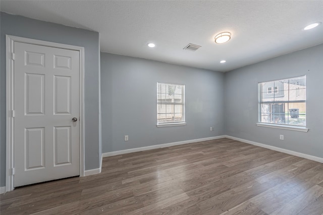 empty room with hardwood / wood-style flooring, a textured ceiling, and a wealth of natural light