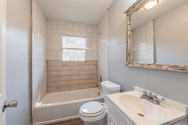 full bathroom featuring tiled shower / bath, vanity, and toilet