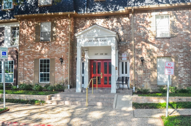 view of front of home featuring french doors, mansard roof, roof with shingles, and brick siding