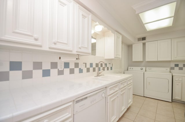 laundry area featuring light tile patterned floors, visible vents, washing machine and dryer, a sink, and laundry area