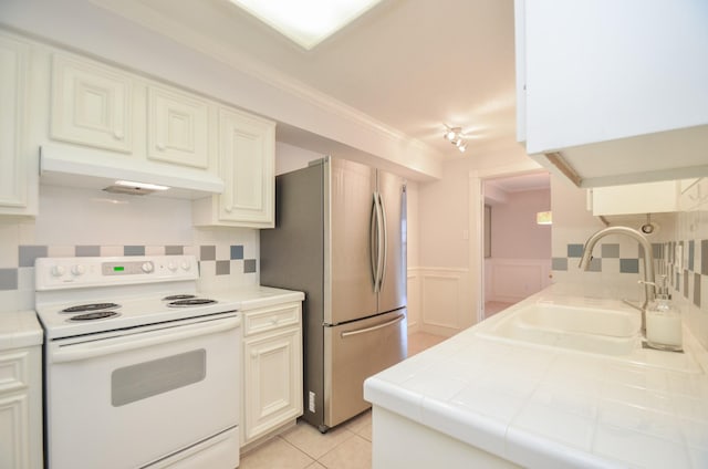 kitchen featuring electric range, freestanding refrigerator, wainscoting, a sink, and under cabinet range hood