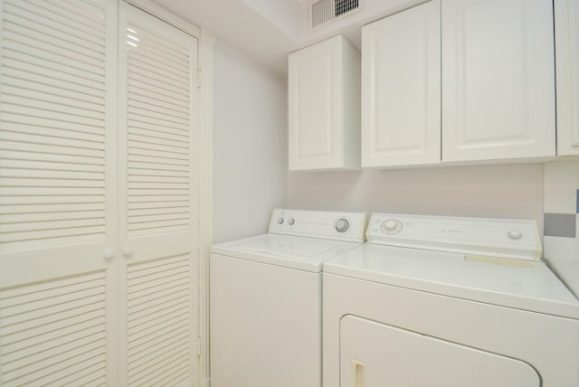 washroom with visible vents, washing machine and clothes dryer, and cabinet space