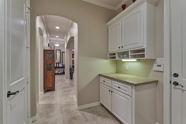 kitchen featuring light tile patterned flooring, light stone countertops, crown molding, and white cabinetry