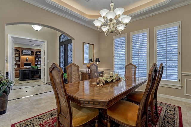 dining space with a healthy amount of sunlight, ceiling fan with notable chandelier, light tile patterned flooring, and crown molding