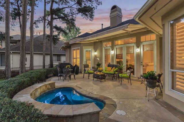 pool at dusk with a patio area and a jacuzzi