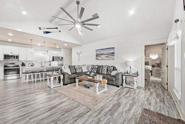 living room featuring ceiling fan, lofted ceiling with beams, and light hardwood / wood-style flooring