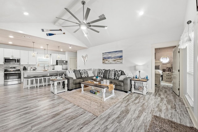 living room with ceiling fan, light wood finished floors, recessed lighting, beamed ceiling, and high vaulted ceiling