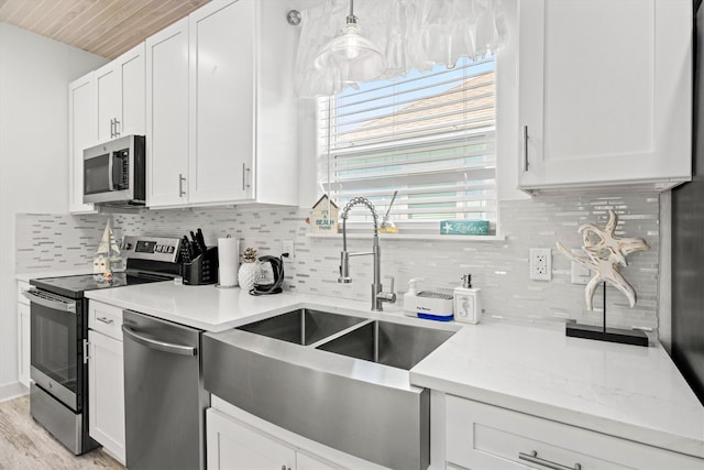 kitchen featuring pendant lighting, sink, white cabinets, stainless steel appliances, and light hardwood / wood-style flooring