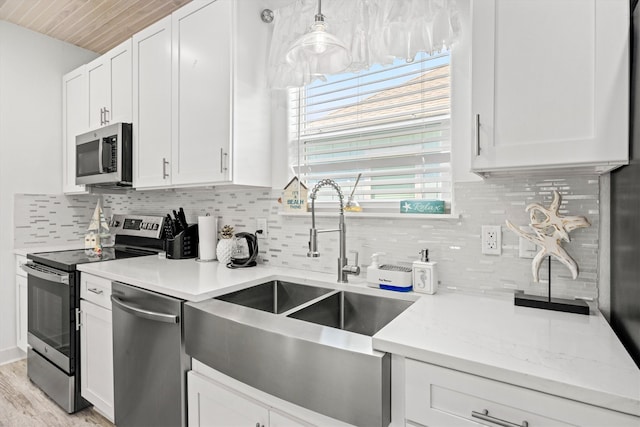 kitchen with stainless steel appliances, a sink, white cabinetry, backsplash, and wooden ceiling