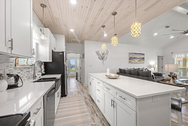 kitchen with light wood-style floors, ceiling fan, open floor plan, a kitchen island, and backsplash