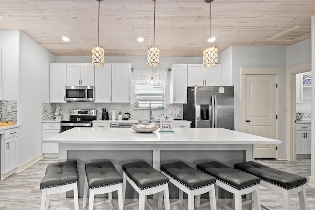 kitchen featuring hanging light fixtures, wood ceiling, white cabinets, and appliances with stainless steel finishes