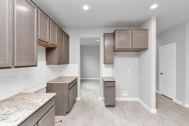 19726 Vino Vale Dr, Hockley, TX 77447 - kitchen with light wood-type flooring, recessed lighting, decorative backsplash, baseboards, and light stone counters