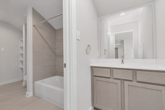 full bathroom featuring vaulted ceiling, tiled shower / bath, vanity, and toilet