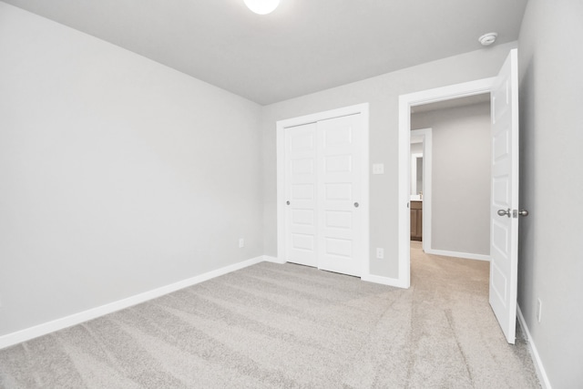 unfurnished bedroom with a closet and light colored carpet