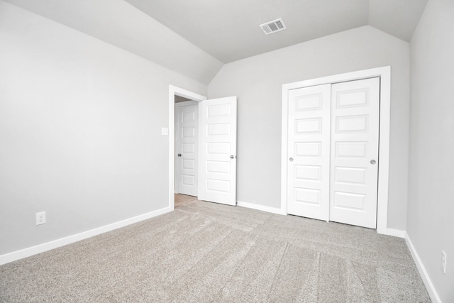 unfurnished bedroom featuring light carpet, lofted ceiling, and a closet