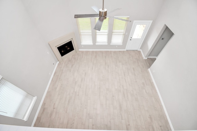 unfurnished living room featuring a high ceiling, light hardwood / wood-style floors, and ceiling fan