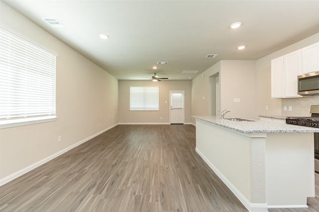 kitchen featuring white cabinetry, gas range oven, ceiling fan, and hardwood / wood-style flooring