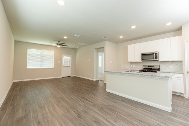 kitchen with light wood-type flooring, ceiling fan, stainless steel appliances, and white cabinets