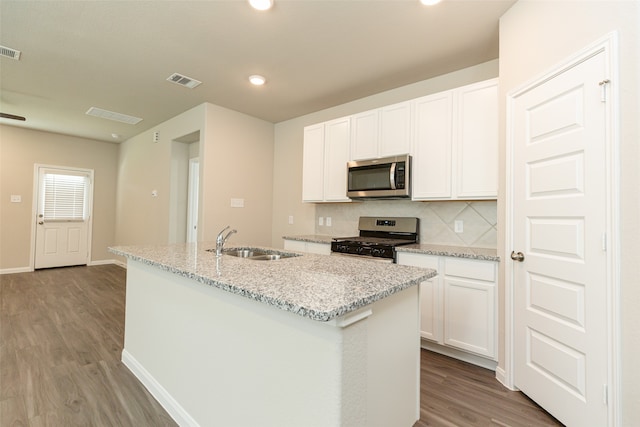 kitchen with appliances with stainless steel finishes, a kitchen island with sink, sink, and white cabinetry