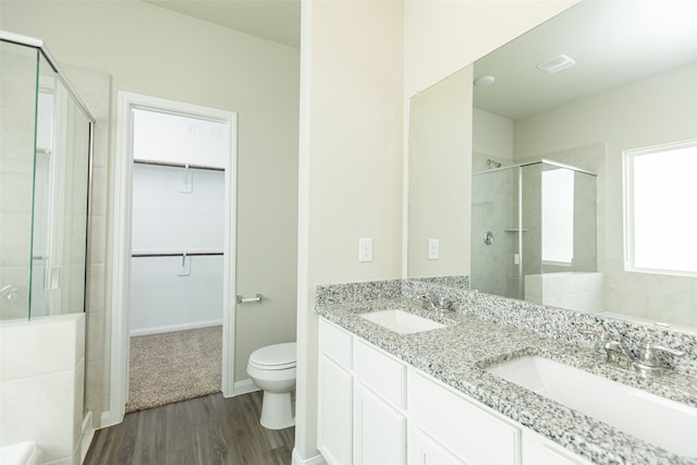 bathroom featuring hardwood / wood-style floors, a shower with door, toilet, and vanity