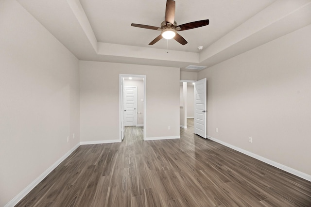 unfurnished bedroom with ceiling fan, dark hardwood / wood-style flooring, and a raised ceiling