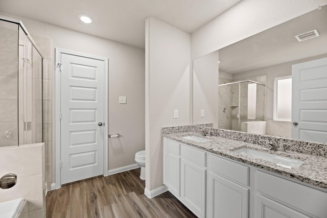 bathroom with toilet, vanity, a shower with shower door, and hardwood / wood-style flooring