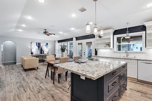 kitchen featuring white cabinetry, dishwasher, ceiling fan, and a wealth of natural light