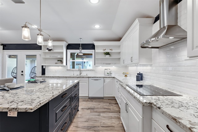 kitchen featuring black electric cooktop, white cabinetry, wall chimney range hood, and decorative light fixtures