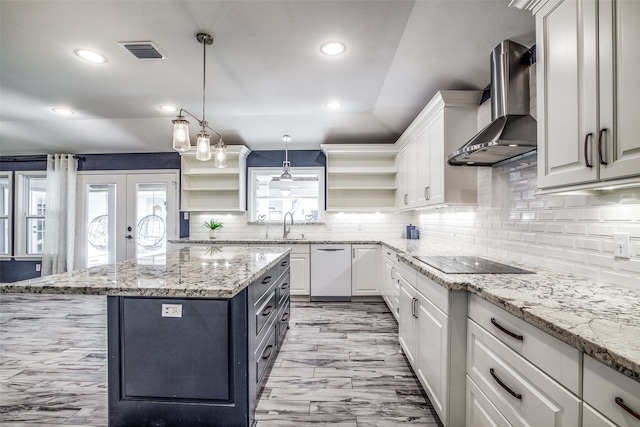 kitchen with light stone countertops, white cabinetry, a center island, and wall chimney range hood