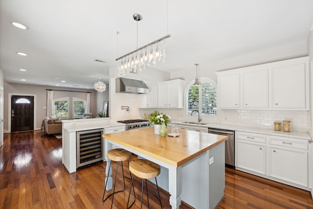 kitchen featuring beverage cooler, white cabinetry, dark hardwood / wood-style flooring, and stainless steel dishwasher