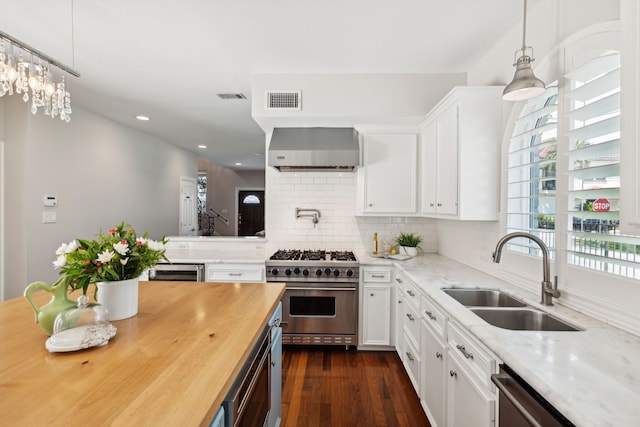 kitchen featuring appliances with stainless steel finishes, wall chimney exhaust hood, white cabinetry, and sink