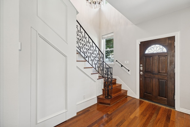 entrance foyer featuring a healthy amount of sunlight, an inviting chandelier, and dark wood-type flooring