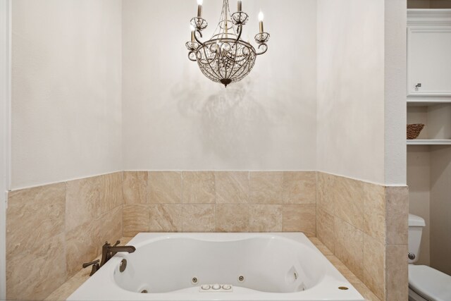 bathroom featuring an inviting chandelier, a tub to relax in, and toilet