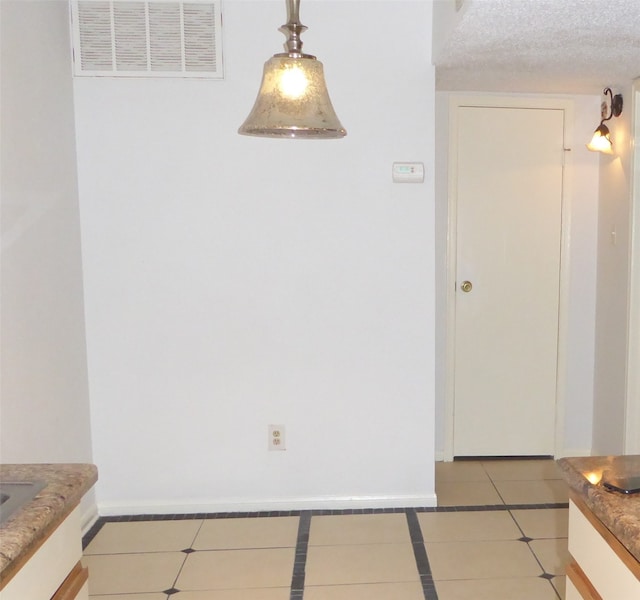 unfurnished dining area with a textured ceiling and light tile patterned flooring