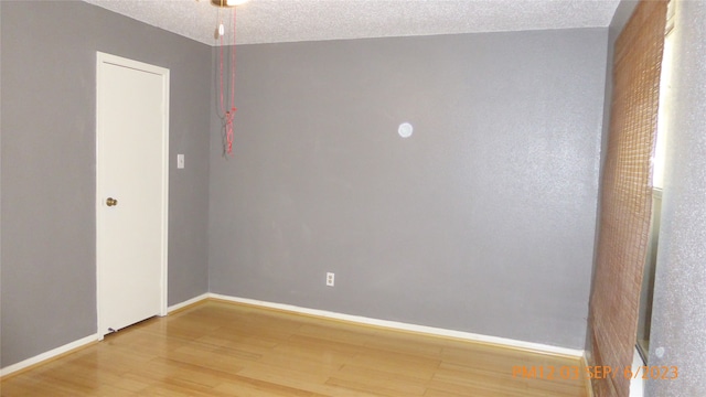 empty room featuring a textured ceiling and hardwood / wood-style floors