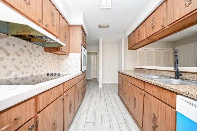 kitchen featuring decorative backsplash, sink, light hardwood / wood-style floors, and white appliances