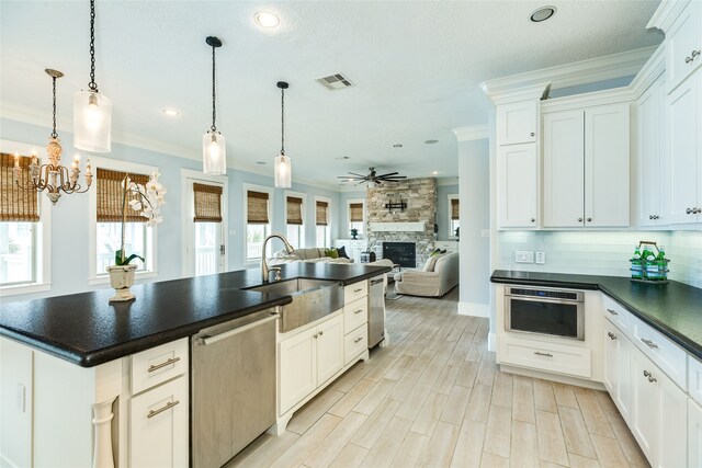 kitchen with visible vents, dark countertops, a fireplace, crown molding, and stainless steel dishwasher