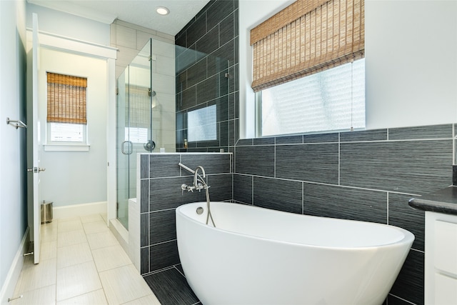 full bath with a freestanding tub, vanity, tile walls, a stall shower, and tile patterned floors