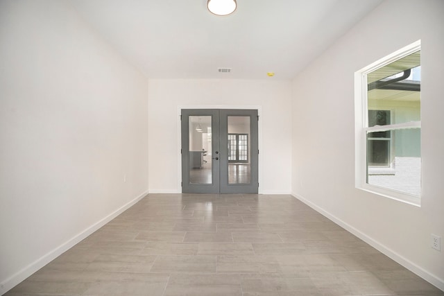 empty room with light hardwood / wood-style flooring, plenty of natural light, and french doors