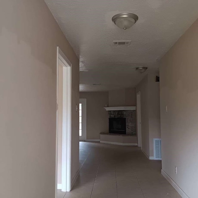 hallway with a textured ceiling and light tile patterned floors