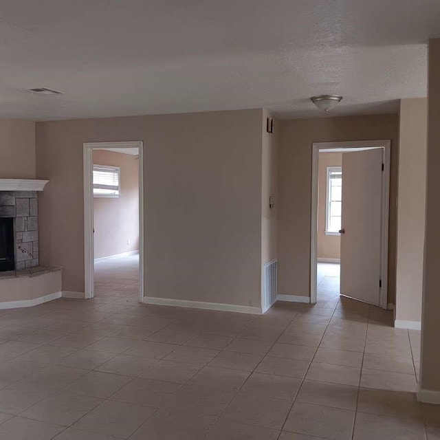 interior space featuring light tile patterned flooring, a tiled fireplace, and a textured ceiling